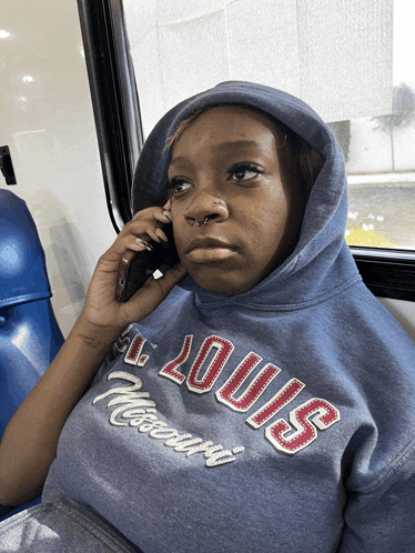 a woman wearing a louis missouri sweatshirt is talking on her phone