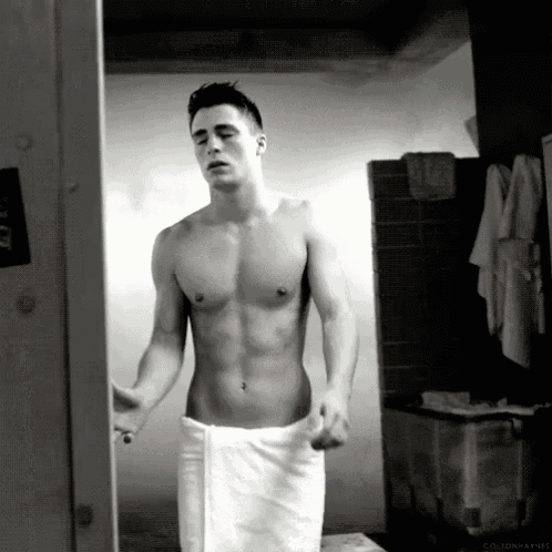 a shirtless man is wrapped in a white towel in a bathroom .