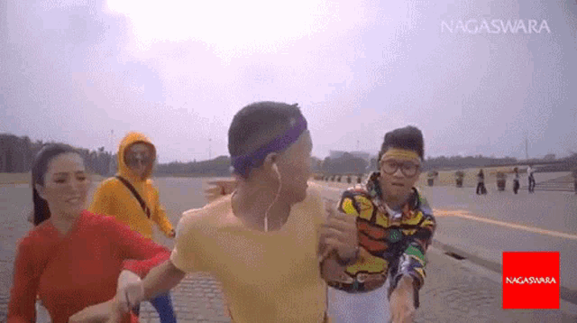 a group of people are running on a road with the word nagasara on the bottom