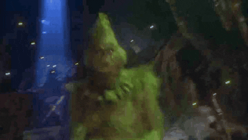 a close up of a green monster in a dark room with a blue light coming out of it .
