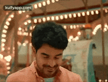 a man is standing in front of a carousel and smiling .