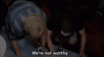 a couple of people standing next to each other with the words `` we 're not worthy '' written on the screen .