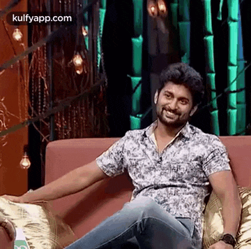 a man is sitting on a couch and smiling .
