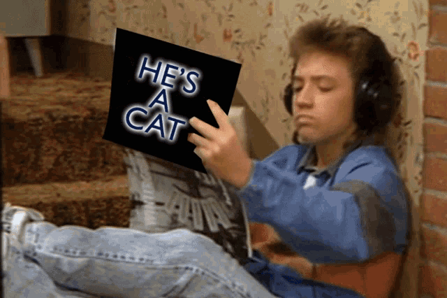 a man wearing headphones is reading a book called he 's a cat