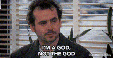 a man is sitting in front of a window with blinds and says `` i 'm a god , not the god ''