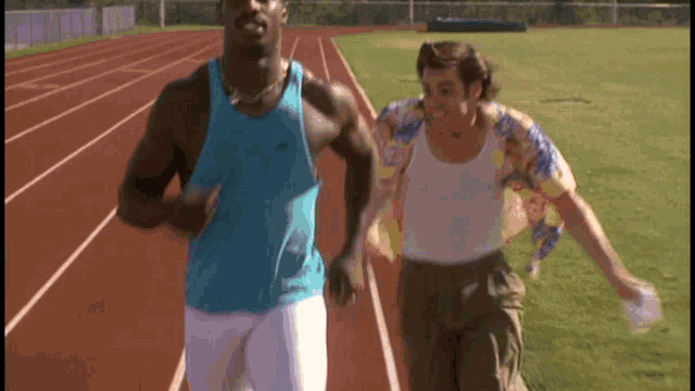 a man in a blue tank top is running on a track with another man