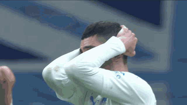a man in a white shirt with the letter y on it holds his head