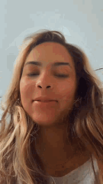 a woman with long hair is making a funny face with her eyes closed .
