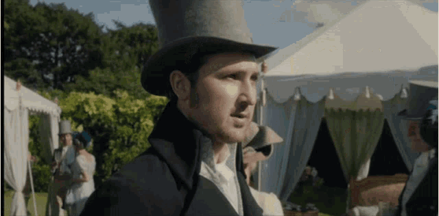 a man in a top hat stands in front of a tent