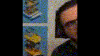 a man wearing headphones and glasses is standing in front of a wall with a stack of lego blocks .