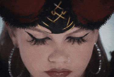 a close up of a woman 's face with her eyes closed and a nose ring