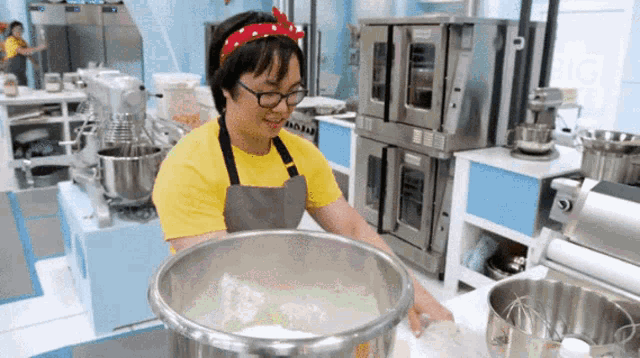 a woman wearing glasses and a yellow shirt is standing in a kitchen