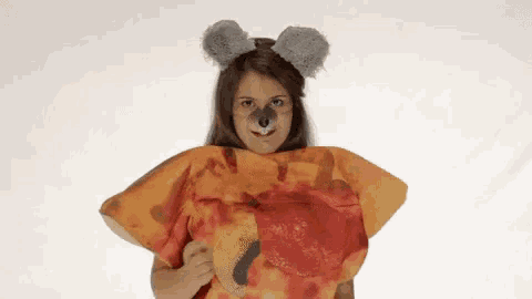 a woman is wearing a koala costume and holding a pizza .