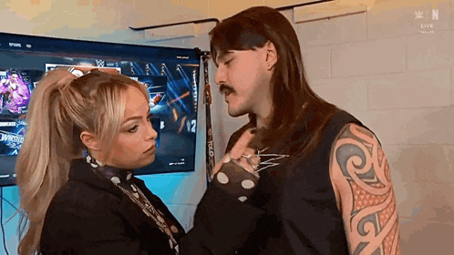 a man and a woman are standing next to each other in front of a tv .