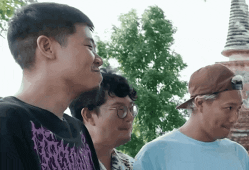 a man wearing a purple shirt with a skull on it is standing next to two other men