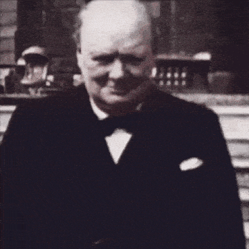 a man in a tuxedo and bow tie is standing in front of some stairs .