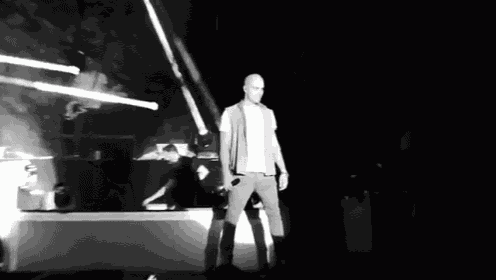 a man is singing into a microphone on a stage in the dark .