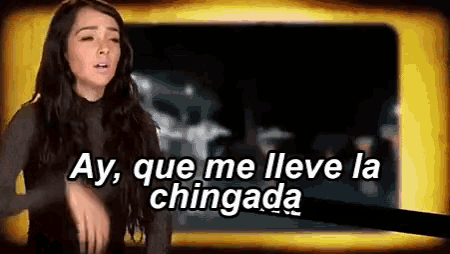 a woman is standing in front of a screen that says ay , que me lleva la chingada