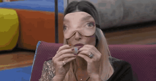 a woman with a mask on her face is sitting on a couch