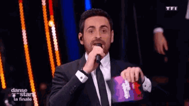 a man in a tuxedo singing into a microphone with the words danse stars la finale on the bottom right