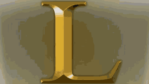 a close up of a gold letter l on a white background .