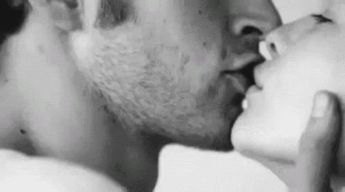 a black and white photo of a man and a woman kissing .