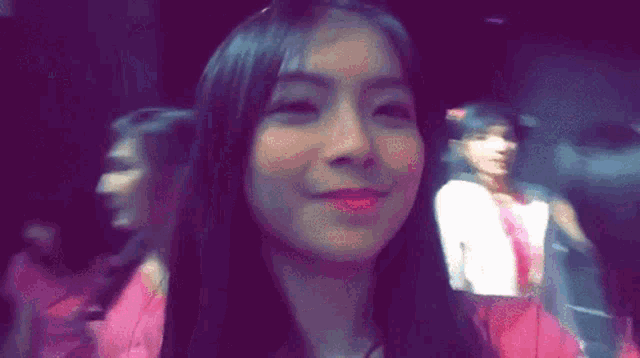 a woman in a pink dress is smiling and looking at the camera .