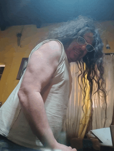 a man with long hair is wearing sunglasses and a tank top