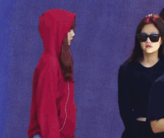 a woman in a red hoodie is standing next to a woman in a black shirt .