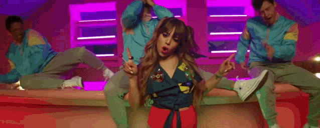 a woman is dancing in a room with a group of men .