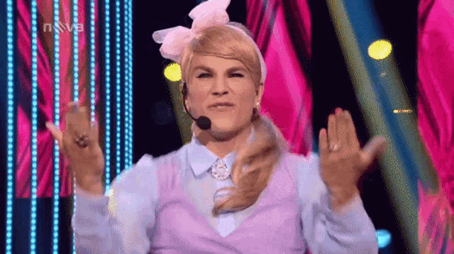 a woman is wearing a wig and a headset while standing on a stage .