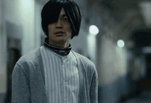 a man with a collar around his neck is wearing a grey sweater