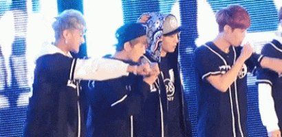 a group of young men are standing next to each other on a stage holding hands .