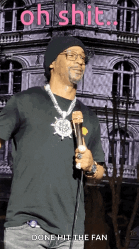 a man holding a microphone with the words oh shit done hit the fan behind him