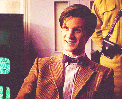 a man in a suit and bow tie is smiling in front of a clock