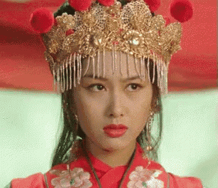 a woman in a red dress and a gold crown on her head .