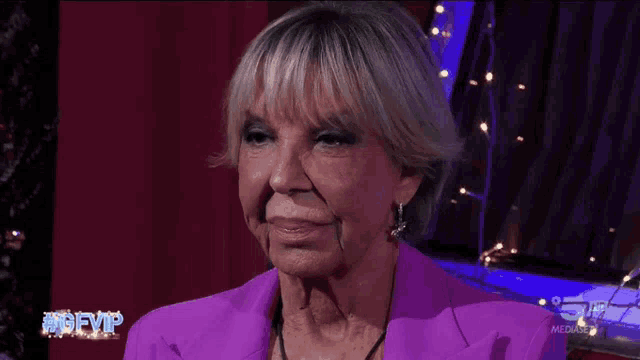 an older woman wearing a purple jacket and earrings is on a television show called #gfvip