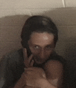 a man talking on a cell phone while holding a baby