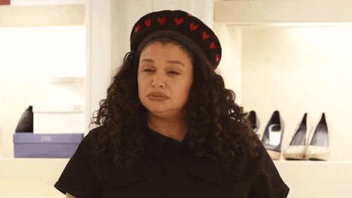 a woman with curly hair wearing a black hat with hearts on it
