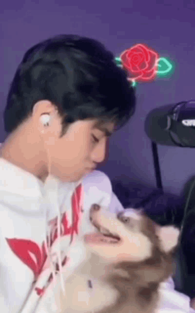 a man wearing headphones is holding a small dog in his lap .