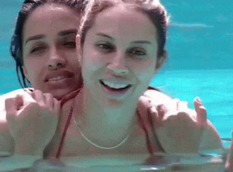 two women are swimming in a pool and one of them is wearing a red bikini