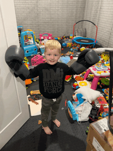 a little boy wearing boxing gloves and a black shirt that says dm dance force