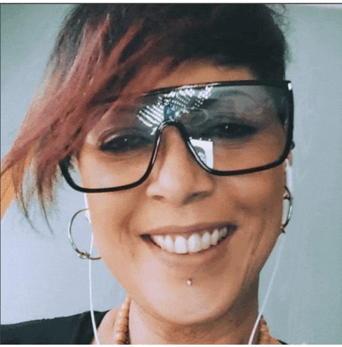 a woman wearing sunglasses and hoop earrings smiles