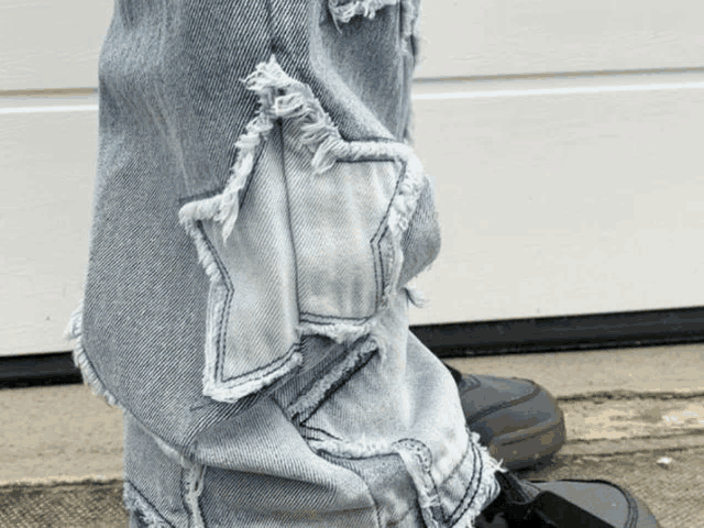 a person wearing a pair of ripped jeans with a star on the side