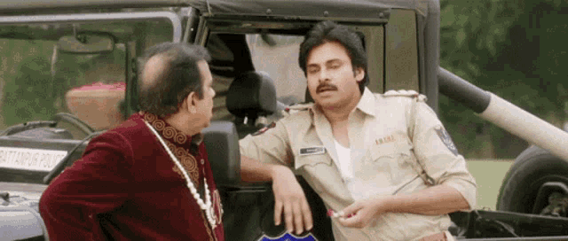 a man talking to a police officer in front of a jeep that says ' pattapur police ' on the side
