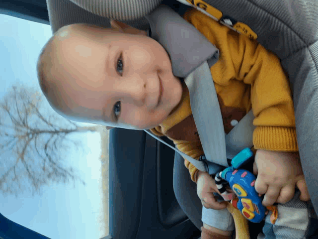 a baby is sitting in a car seat with a toy that says ' abc ' on it