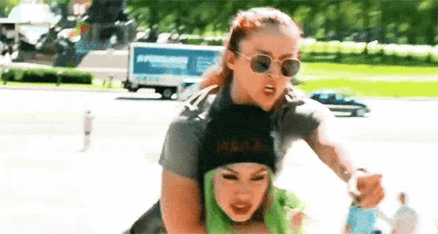 a woman is giving another woman a piggyback ride while wearing sunglasses .