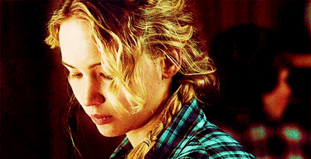a close up of a woman 's face wearing a plaid shirt and braided hair .