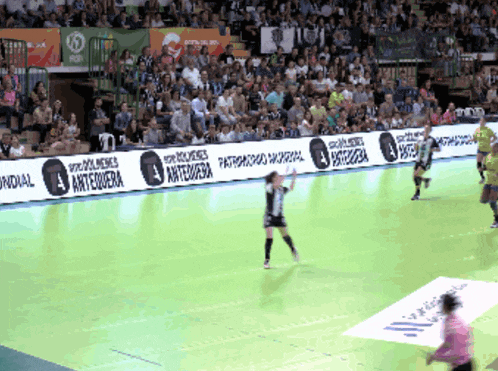 a handball game is being played in front of a crowd with a banner that says antequera on it