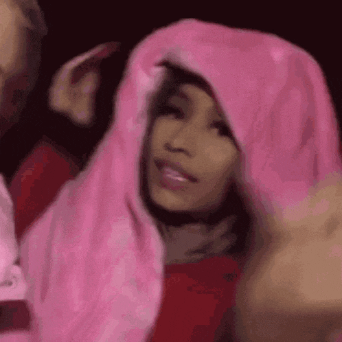 a woman is wearing a pink hooded jacket and a pink blanket .